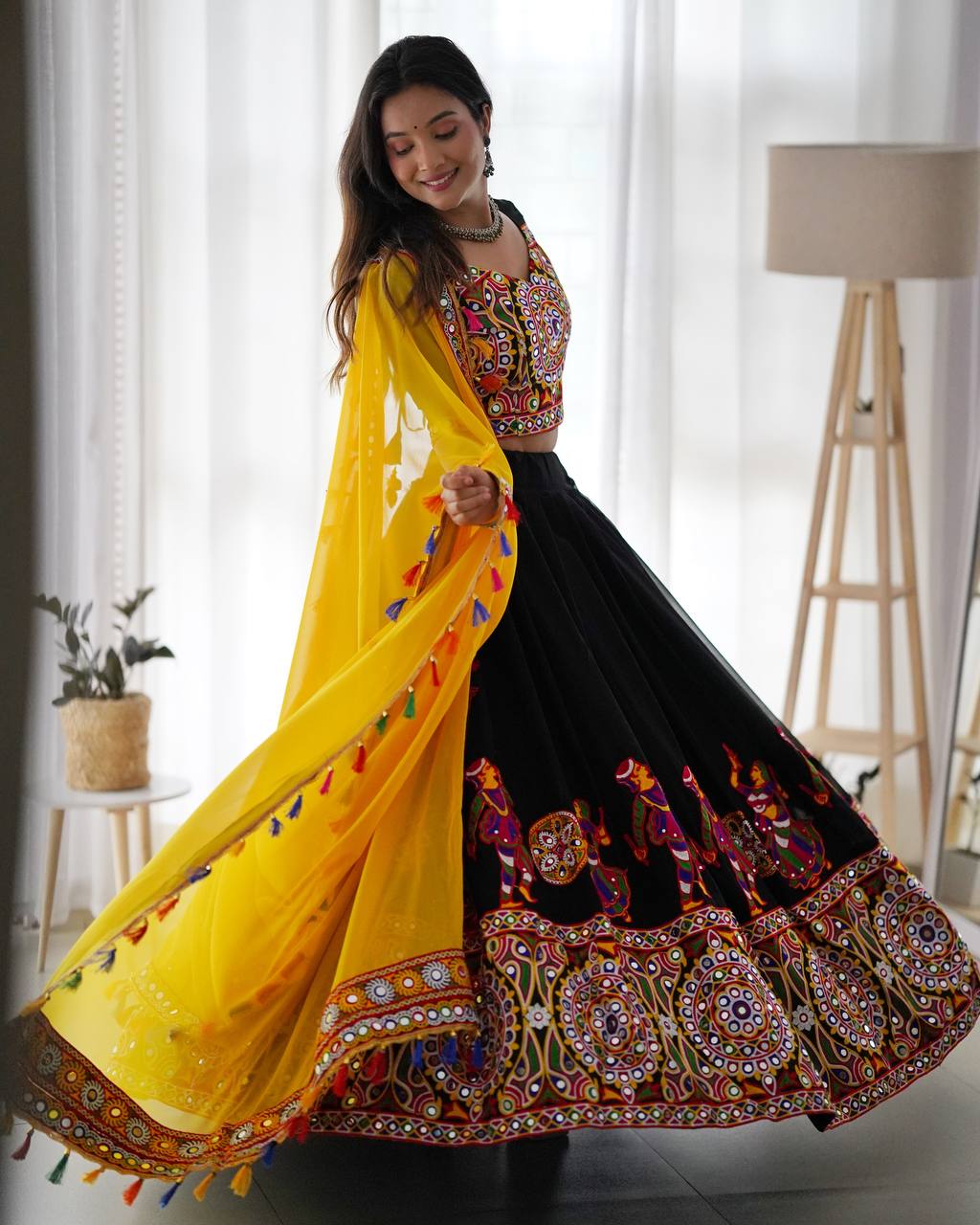 Designer black Garba lehenga choli with multicolor traditional Kutchi embroidery and flowing yellow dupatta, perfect for Navratri and Dandiya celebrations.